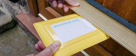 Photograph of yellow wallet being posted through door